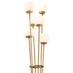 four light brass floor lamp with white glass globes on the top and gold metal base