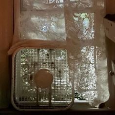 the window is covered with white lace and has a birdcage on it's side