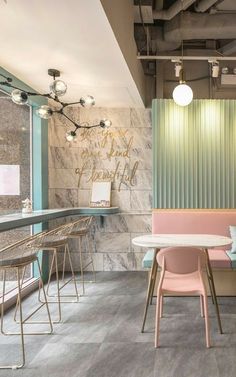 the interior of a restaurant with pink chairs and marble walls, along with tables and stools