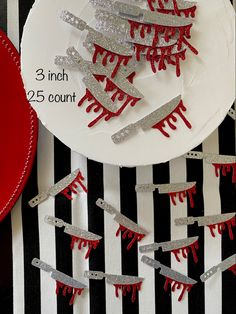 a white plate topped with lots of red and silver glittered hair clips on top of a black and white striped table cloth