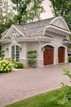 a small house with two garages on the front and one in the back, surrounded by greenery