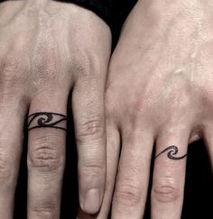 two people with matching rings on their fingers and one has a wave tattoo on the middle finger