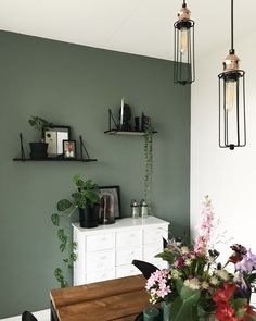 a dining room with green walls and flowers on the table in front of the counter