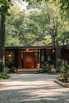 the entrance to a modern home surrounded by trees and shrubs, with stone walkway leading up to the front door