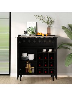 a black cabinet with wine glasses and plates on it in front of a wall mounted plant