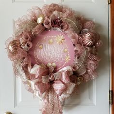 a pink and gold christmas wreath hanging on the front door