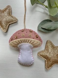 a mushroom ornament hanging from a string next to two star shaped ornaments on a table