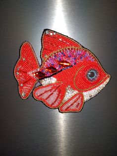 a red fish is sitting on top of a metal surface