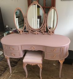 a pink vanity with two stools and a mirror