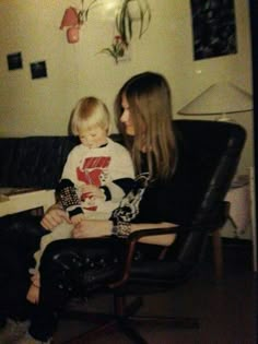 a woman sitting next to a little boy in a chair