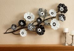 a metal flower sculpture on a mantle next to a white candle and a small lamp