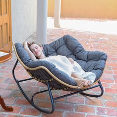 a woman is laying in a chair on the brick floor next to a table and door