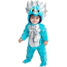 a baby in a blue dragon costume standing on one leg and smiling at the camera