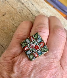 a person's hand with a ring on it that has flowers in the center