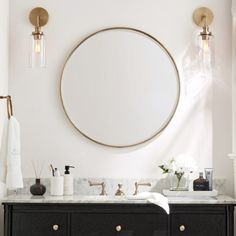 a bathroom with two sinks and a large round mirror above the sink is surrounded by gold fixtures