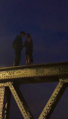 two people standing on top of a bridge at night