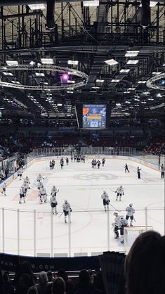 an ice hockey game is being played in a large arena with people watching from the stands