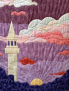 a quilted wall hanging with a clock tower in the sky and clouds above it