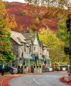 a car is driving down the road in front of some houses with autumn foliage on them