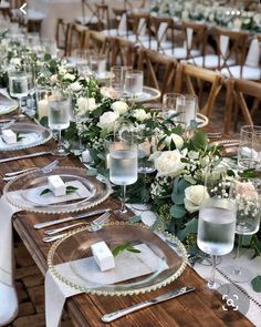 the table is set with white flowers and greenery for an elegant dinner or reception