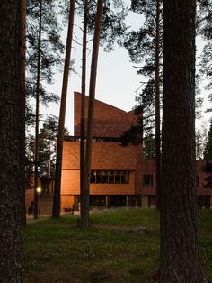 the house is surrounded by tall trees and has a red brick facade on it's side