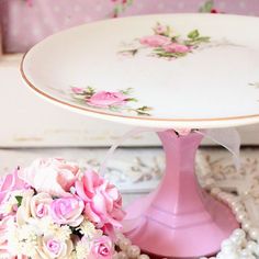 a pink cake stand with flowers on it