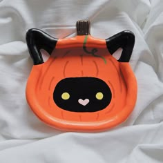 an orange plastic plate with a black cat on it's face and eyes painted onto the surface