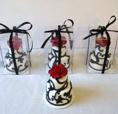 three small cakes with black and white designs on them are wrapped in red ribbon bows