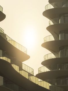 the sun shines brightly in front of a building with spirally balconies