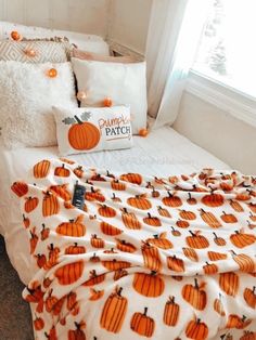 a bed with pumpkins on it and white pillows in front of a window,