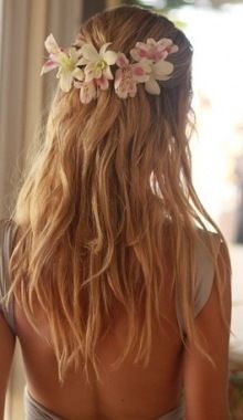 the back of a woman's head with long hair and flowers in her hair