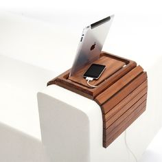 an apple laptop is sitting on top of a wooden charging station that also holds a cell phone