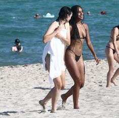 two women in bikinis walking on the beach