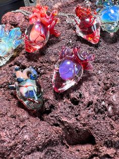 four glass turtle necklaces sitting on top of a rock