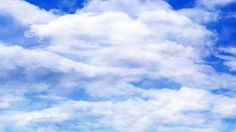 a group of people standing on top of a sandy beach under a blue cloudy sky