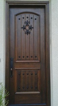 the front door is made of wood and has decorative iron work on it's side