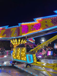 an amusement park ride at night with people riding on the rides and lights in the background