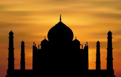 the silhouette of an ornate building against a sunset sky with clouds in the back ground