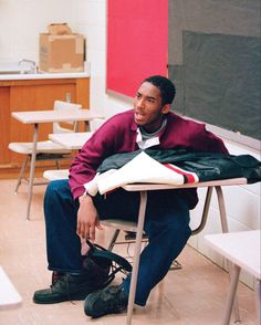 a man sitting at a desk in a classroom with his foot propped up on the table