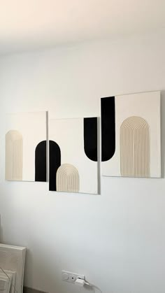 three black and white paintings hanging on the wall