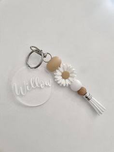 a keychain with a daisy on it and the word willow written in white