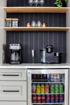 an open refrigerator in a kitchen next to some shelves with cups and glasses on it