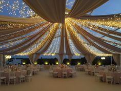 the inside of a tent with tables and chairs set up for a wedding or other function