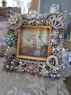 an old photo frame is adorned with glass beads