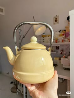 a person holding a yellow teapot in their hand