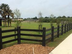 a black fence in front of a grassy field