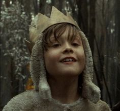 a young boy wearing a crown in the woods