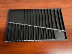 four black trays sitting on top of a wooden table next to an empty bottle