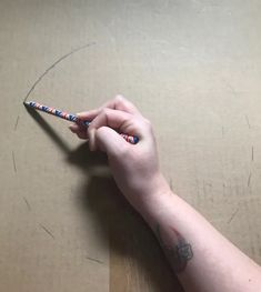 a person holding a pencil in their left hand on top of a cardboard box with writing on it