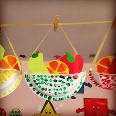 an image of fruit in a bowl hanging from clothes pins